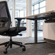 BIFMA compliant ergonomic mesh office chair and height adjustable standing desk in a modern corporate workspace