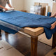 Movers wrapping wooden dining table with moving blanket and corner guards
